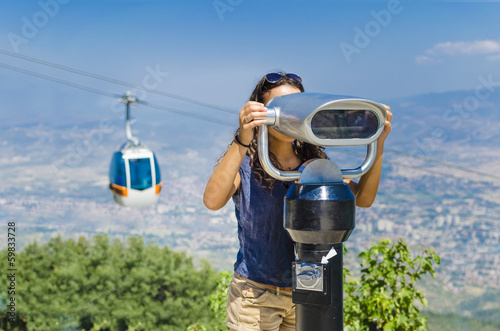 Beautiful girl  is looking at coin operated binocular