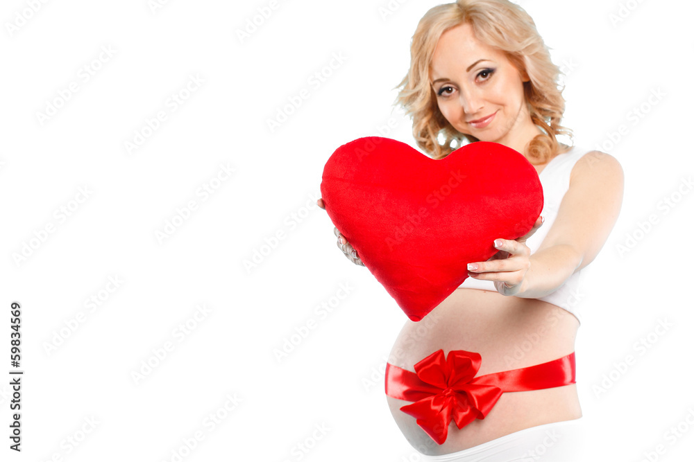 Pregnant woman holding a red heart pillow in hand on white Pregnant woman holding a red heart pillow in hand on white