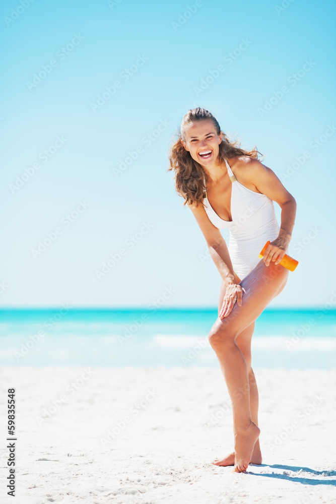 Full length portrait of smiling woman applying sun screen creme Full length portrait of smiling woman applying sun screen creme
