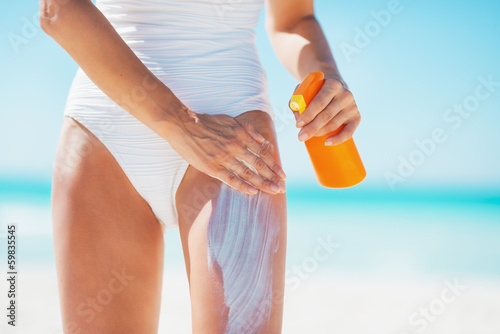 Closeup on young woman applying sun block creme on beach