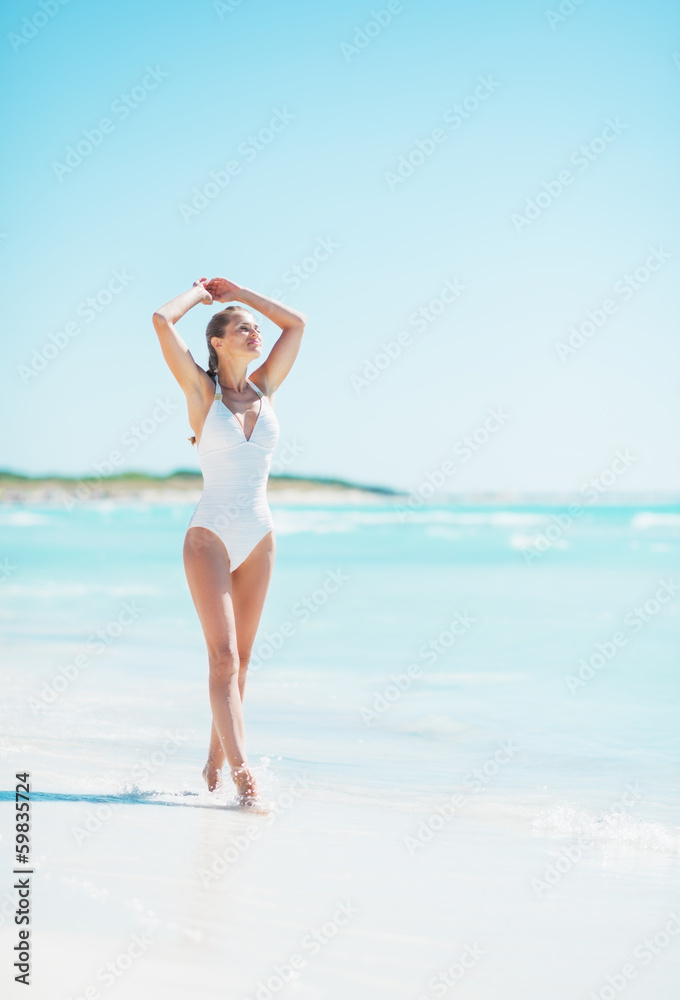 Full length portrait of young woman walking on sea shore Full length portrait of young woman walking on sea shore