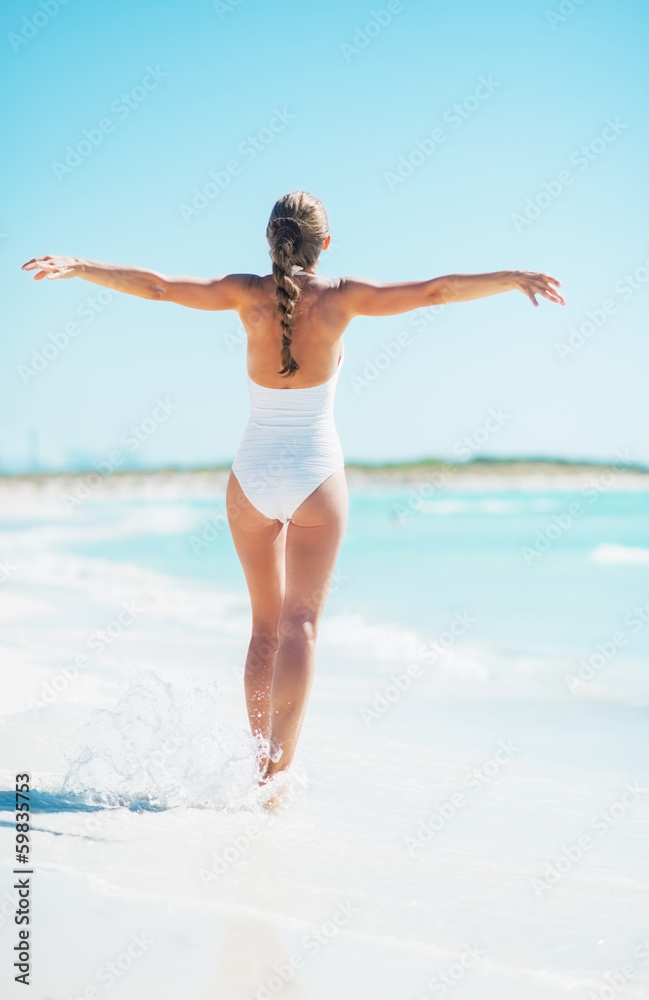Full length portrait of young woman rejoicing on beach