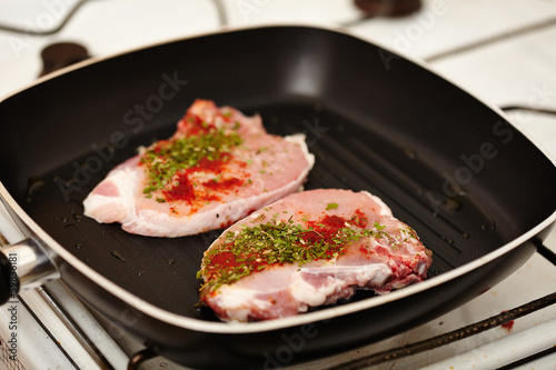 Spiced raw pork chops in the frying pan