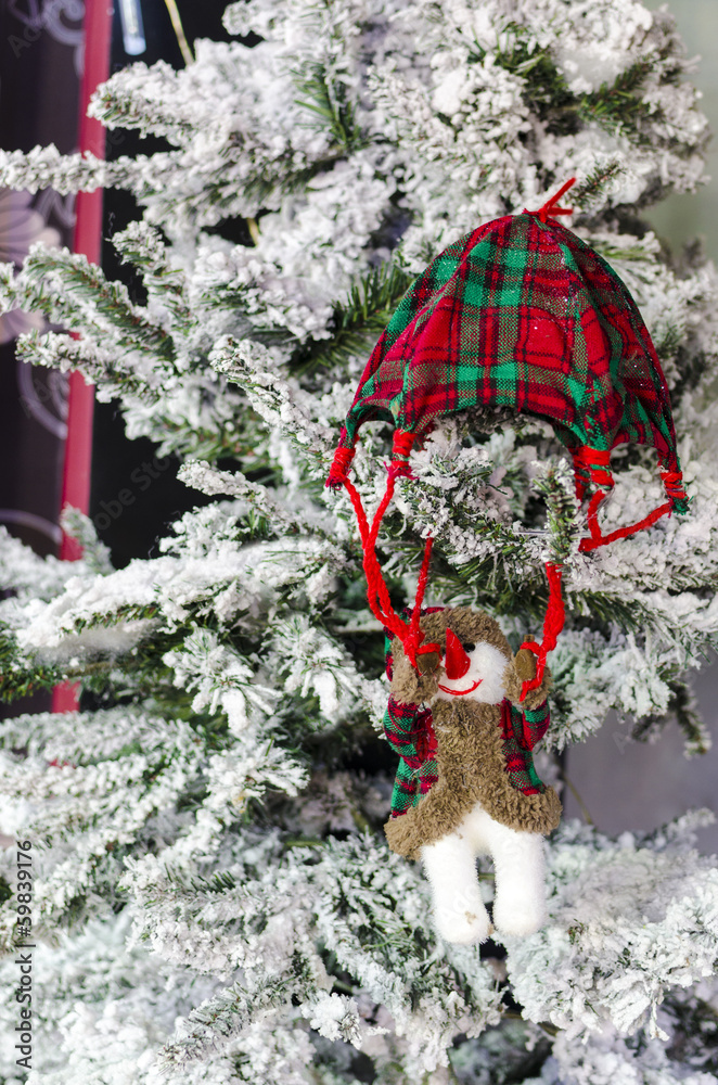Snowman parachute decoration on pine tree with snow Snowman parachute decoration on pine tree with snow