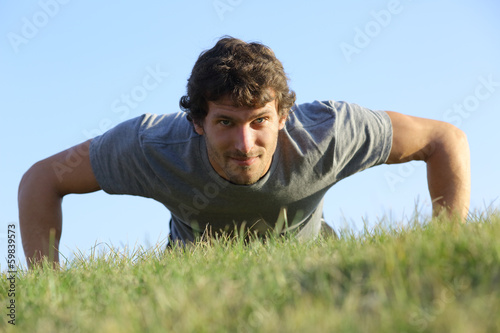 Close up of a man doing pushups on the grass