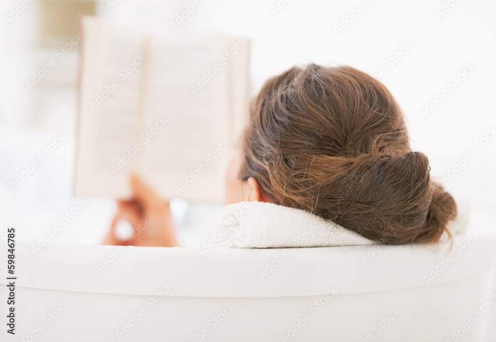 Young woman reading book in bathtub. rear view - obrazy, fototapety, plakaty 