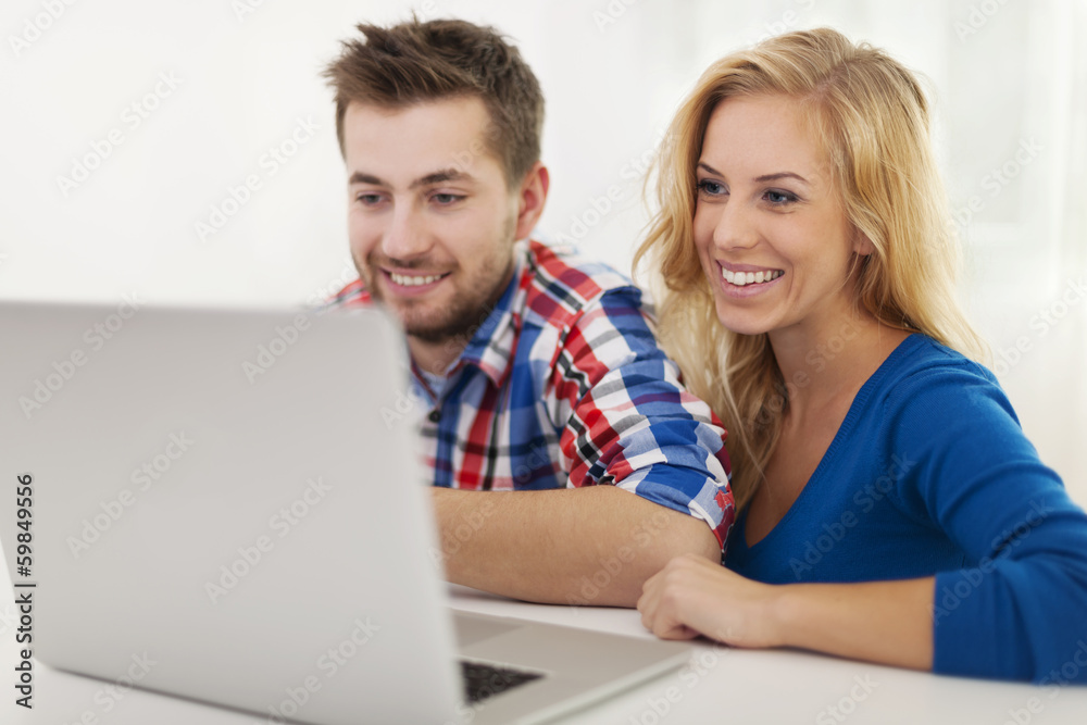 Smiling couple looking on laptop at home