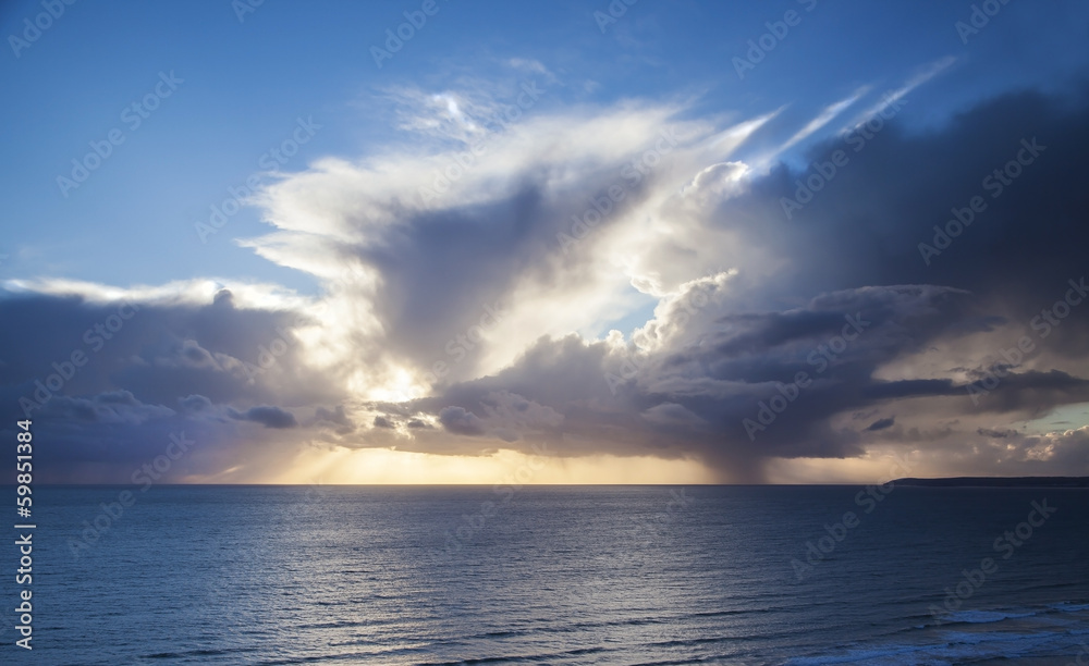 Seascape with sunset rays behind clouds over oce