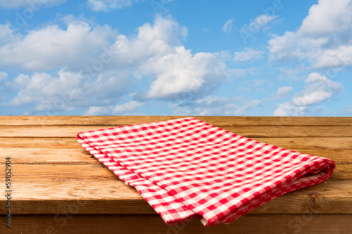 Red checked tablecloth and empty deck wooden table