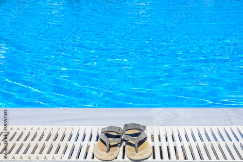 Leather sandals are on the edge of the swimming pool