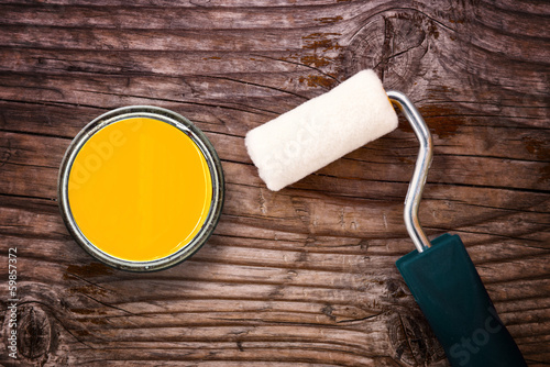 Paint roller and color tin can on wooden background