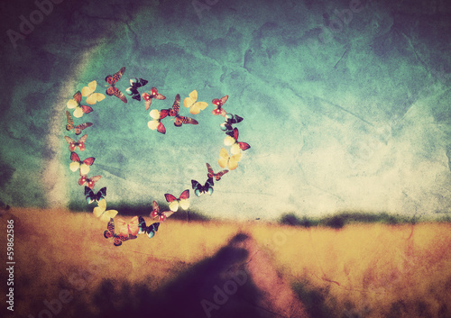Heart shape made of butterflies on vintage field background