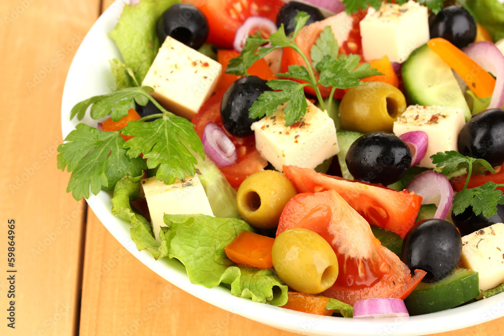 Fresh salad in plate on wooden table