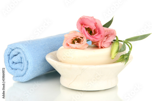 Rolled blue towel, soap bar and beautiful flower isolated