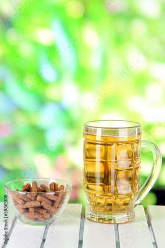 Beer in glass and croutons on table on nature background