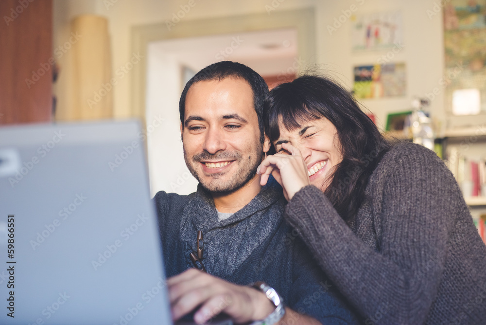 couple in love using notebook at home couple in love using notebook at home