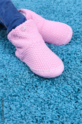 Female legs in home winter shoes, on blue carpet background