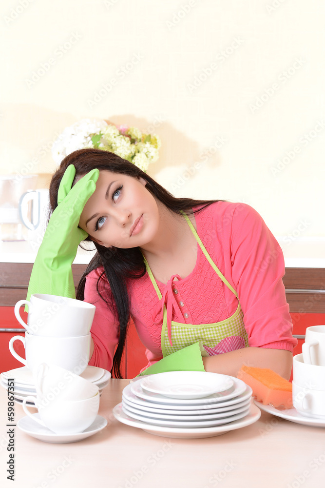 Beautiful young woman wipes clean utensils in kitchen Beautiful young woman wipes clean utensils in kitchen