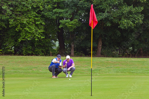 Golfer and caddy putting green. photo
