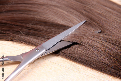 Long brown hair and scissors on wooden background