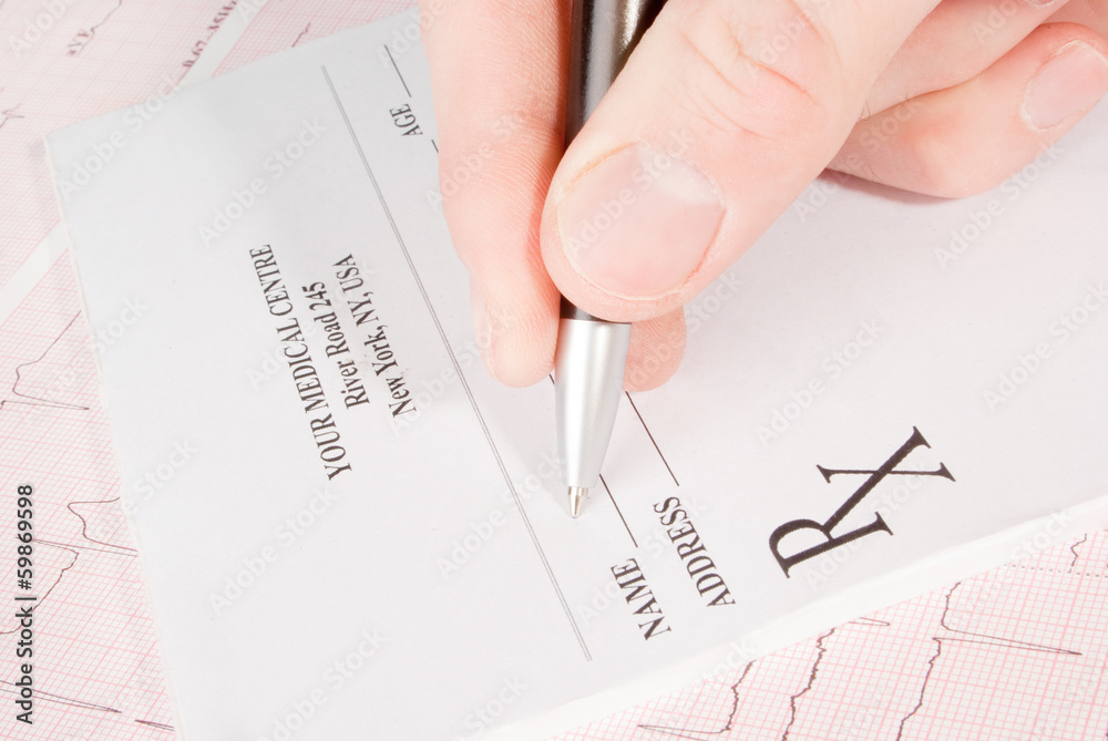Doctor filling in empty medical prescription on ECG Doctor filling in empty medical prescription on ECG