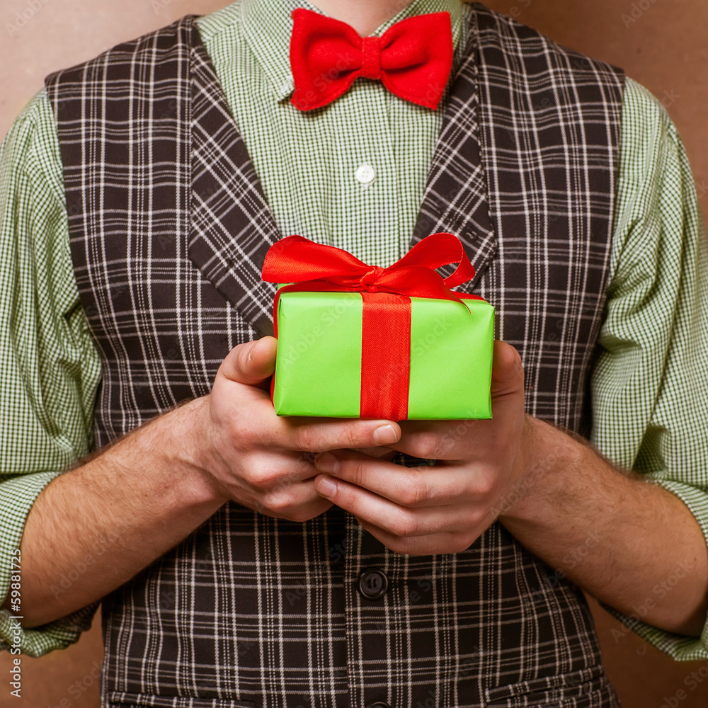 guy holding a gift in a suit and bow tie guy holding a gift in a suit and bow tie