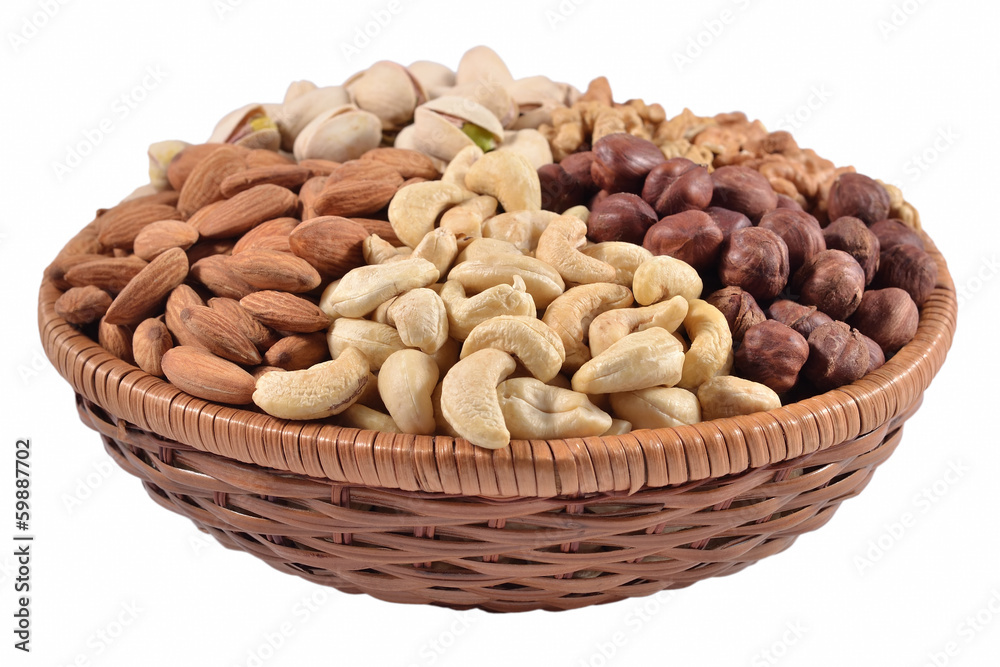 Assorted nuts in a wicker bowl on a white background Assorted nuts in a wicker bowl on a white background