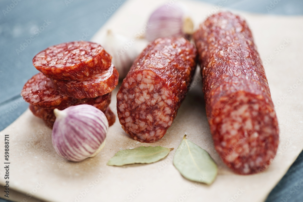 Italian salami, bay leaves and garlic on a packaging paper Italian salami, bay leaves and garlic on a packaging paper