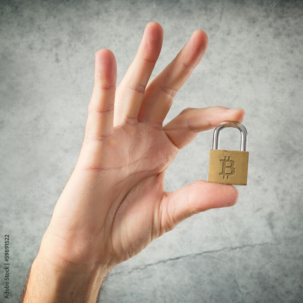 Hand holding padlock with Bitcoin symbol Hand holding padlock with Bitcoin symbol