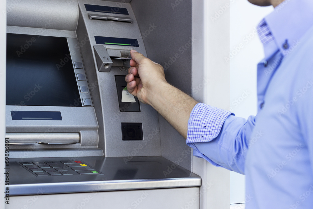 Hand of man with credit card, using a ATM Hand of man with credit card, using a ATM
