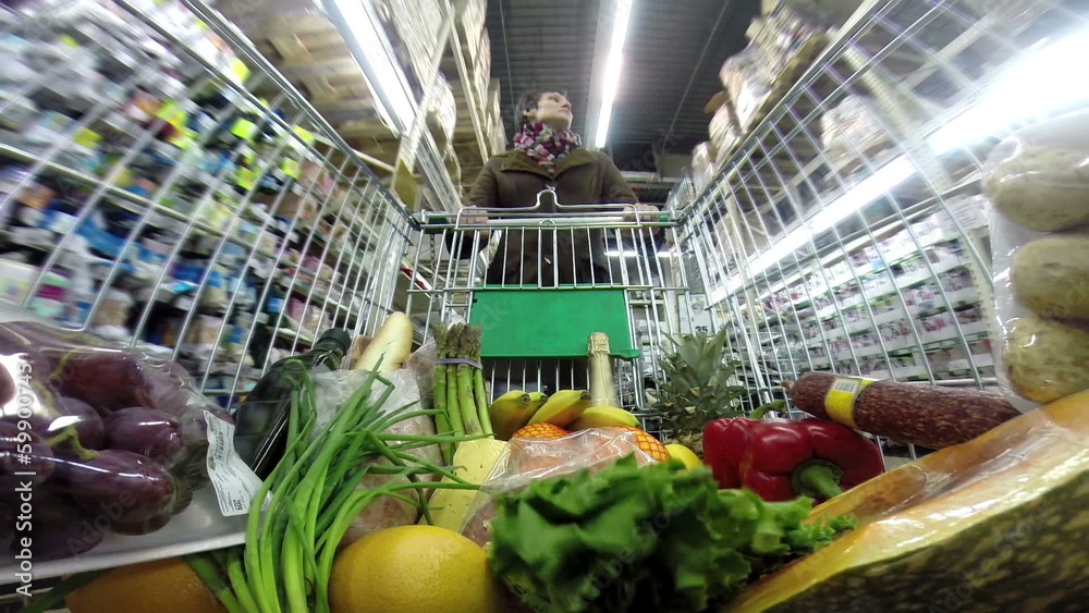 Woman with shopping trolley moves on a supermarket