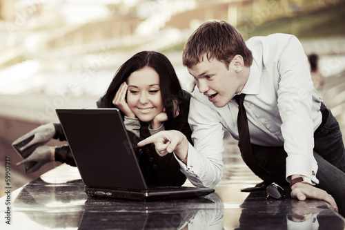 Young business couple using laptop outdoor