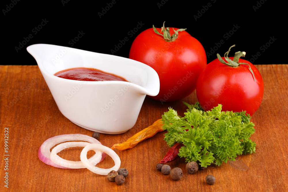 Ketchup and ripe tomatoes on wooden table on black background Ketchup and ripe tomatoes on wooden table on black background