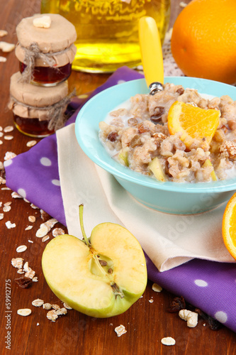 Useful oatmeal in bowl with fruit on wooden table close-up