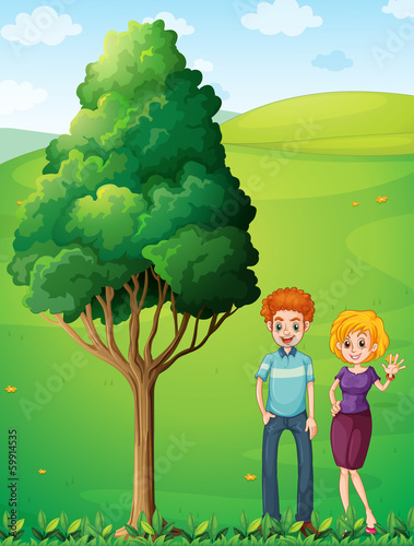 A couple at the hilltop standing near the tree
