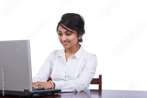 Attractive Asian businesswoman using laptop at her desk