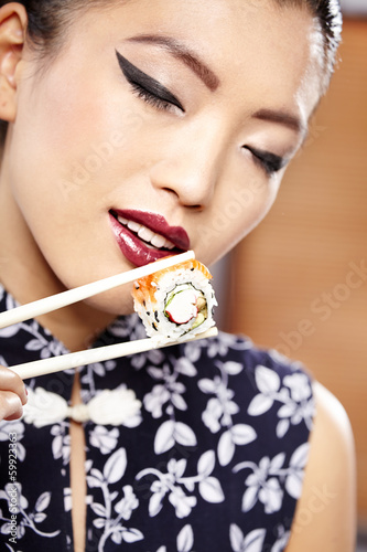 Beautiful young woman eating sushi. Shallow depth of field, focu