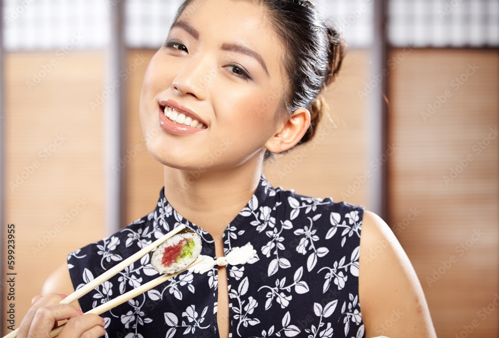 Beautiful young woman eating sushi. Shallow depth of field, focu Beautiful young woman eating sushi. Shallow depth of field, focu