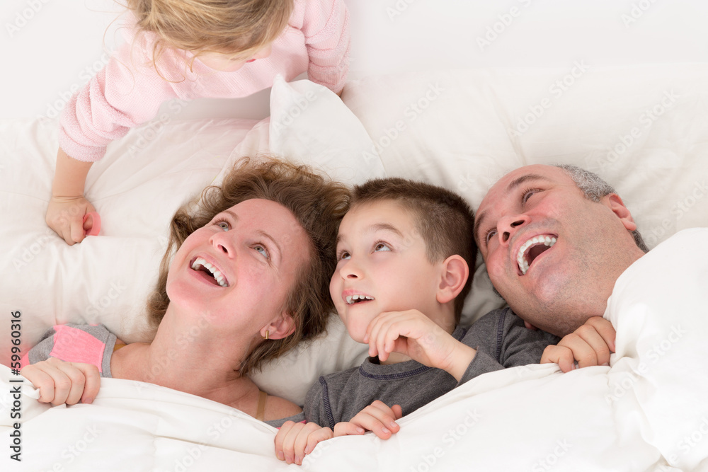 Playful little girl with her family in bed