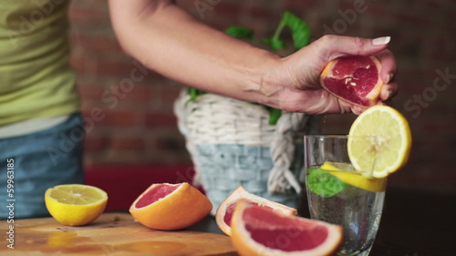 Woman hands squeeze grapefruit into glass, steadicam shot photo