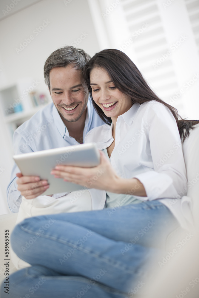 Cheerful couple using digital tablet at home