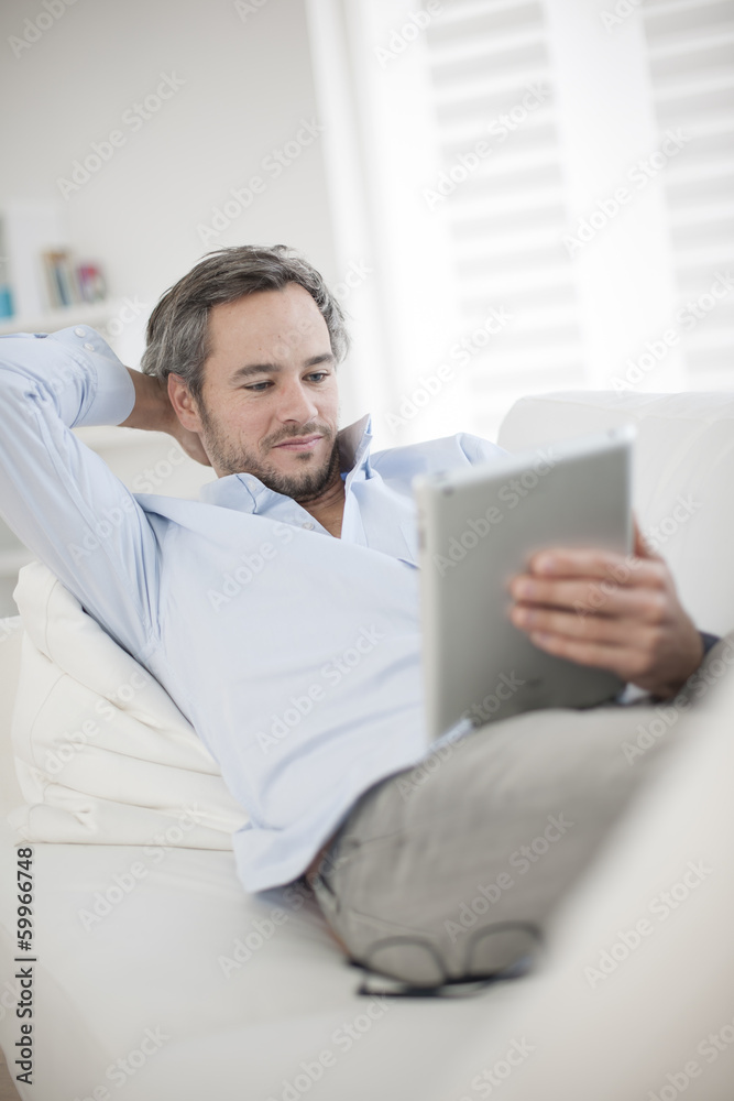 Attractive man at home using digital table Attractive man at home using digital table