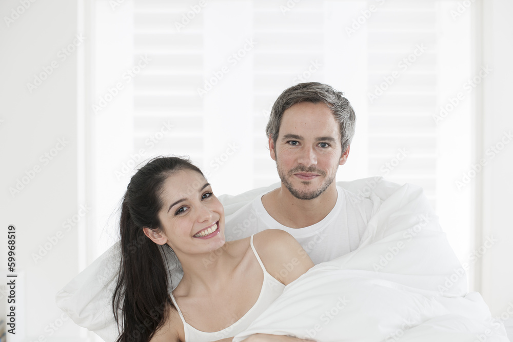 cheerful young couple wrapped in their quilt cheerful young couple wrapped in their quilt