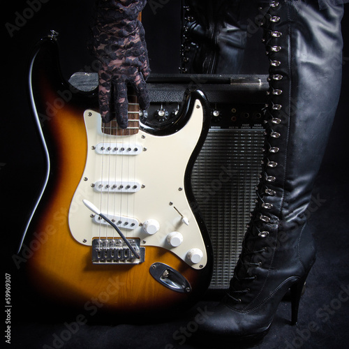Goth Woman Picking Up Guitar In Front of Amplifier