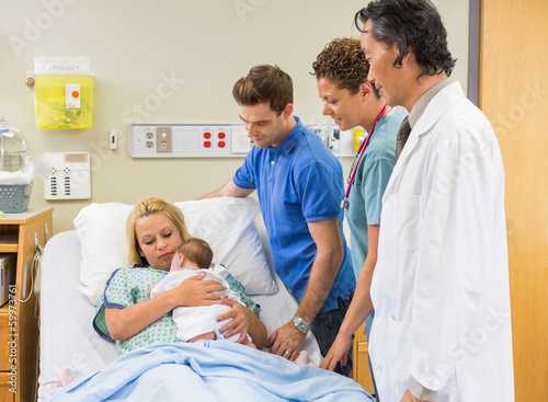 Medical Team And Man Looking At Mother With Babygirl