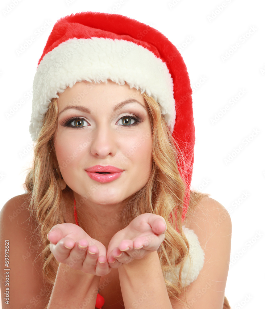 Fototapeta premium Smiling young woman in Santa hat blowing air kiss