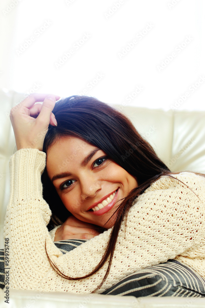 Happy beautiful woman lying on the sofa and looking at camera Happy beautiful woman lying on the sofa and looking at camera