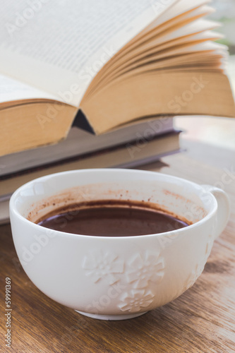 Cup of chocolate on a wooden surface with books