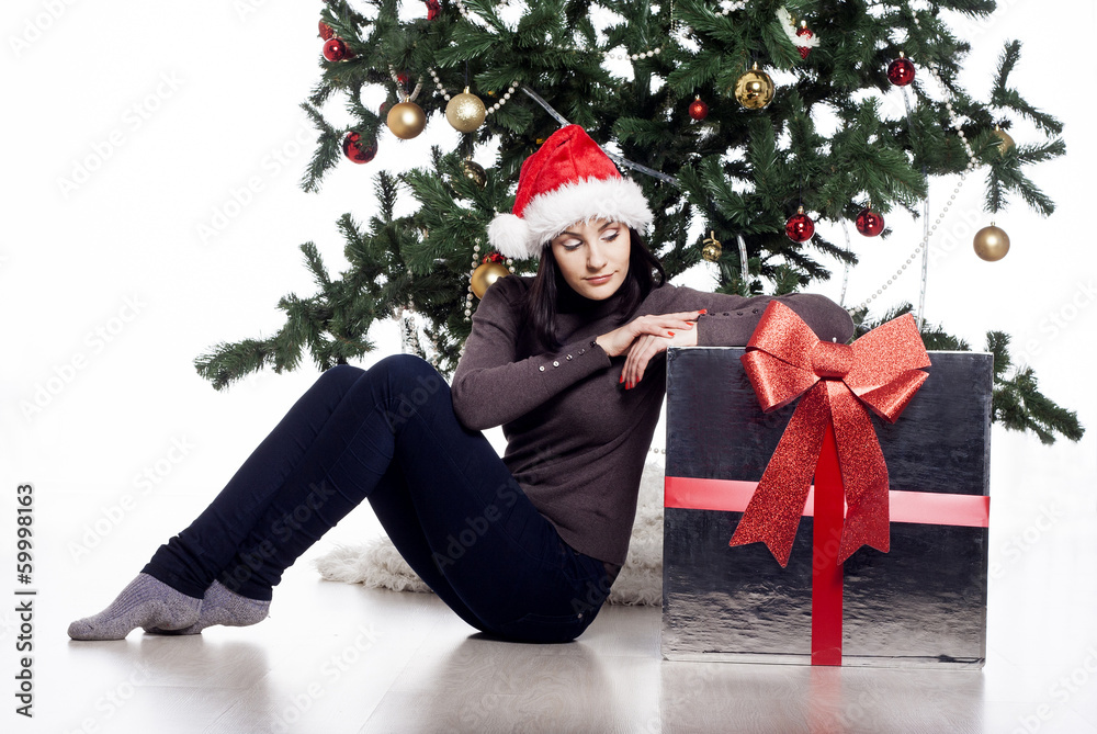 Young woman sitting near xmas tree with present Young woman sitting near xmas tree with present