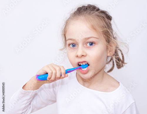 Child girl in pyjamas brushing teeth - bedtime hygiene